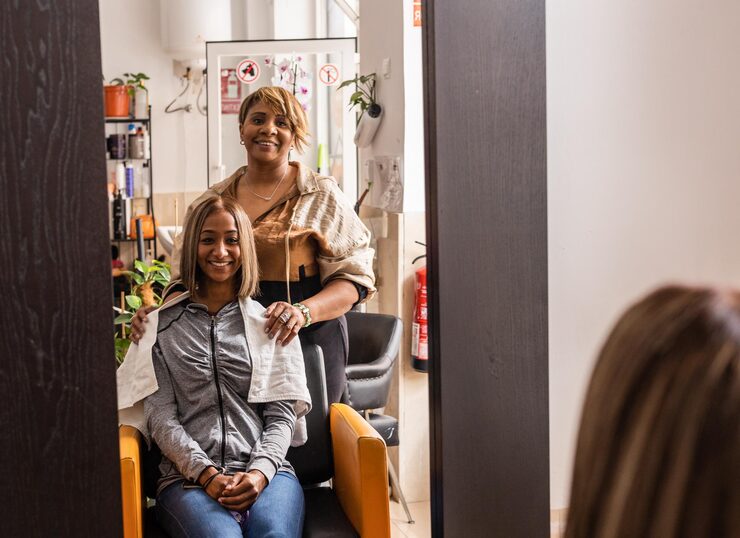 Independent hairstylist standing proudly beside her happy seated client in one of the Sandy Springs salon suites for rent, building her income on her own terms.